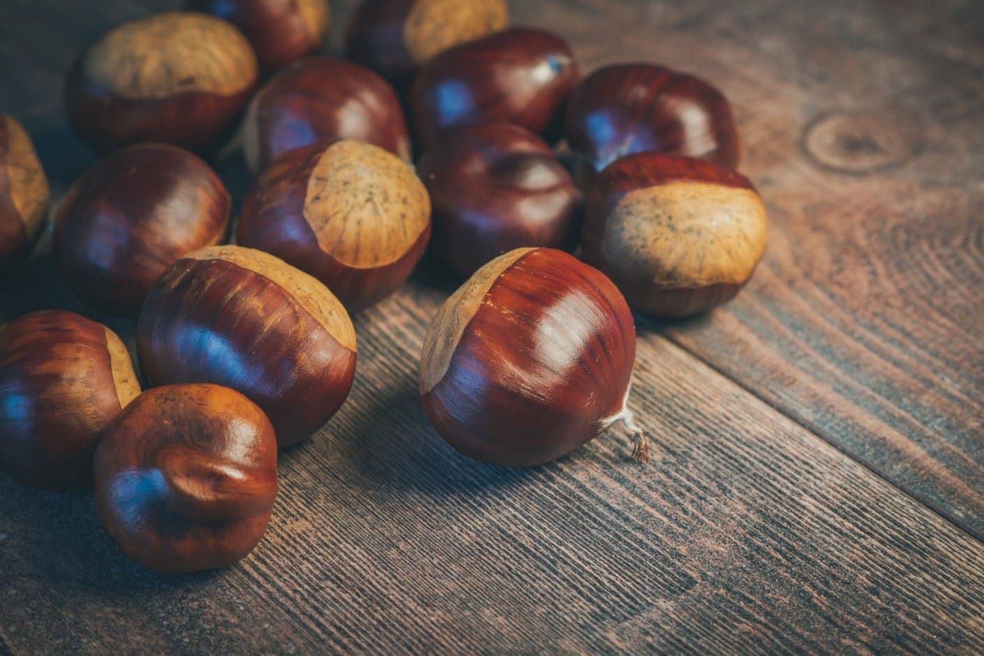 A pile of chestnuts on top of a wooden table.